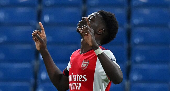 Bukayo Saka celebrating a goal in an Arsenal jersey during a Premier League match.