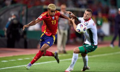 Lamine Yamal in action for Spain, with Luis de la Fuente and Hansi Flick in the background amid injury debate.