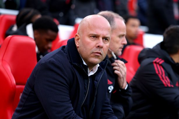 Arne Slot standing on the touchline during a Liverpool match looking under pressure.