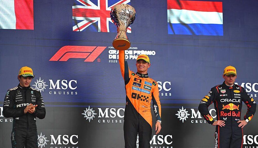 Racing Bulls team member making a thumbs-down gesture during Lando Norris’ Sao Paulo Grand Prix trophy celebration.