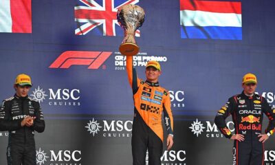 Racing Bulls team member making a thumbs-down gesture during Lando Norris’ Sao Paulo Grand Prix trophy celebration.