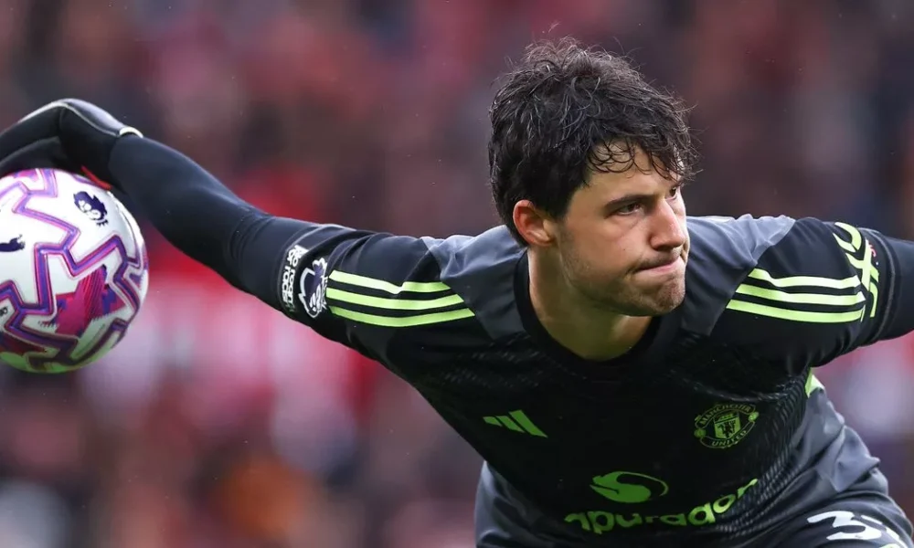 Senne Lammens making a save in a Manchester United jersey.