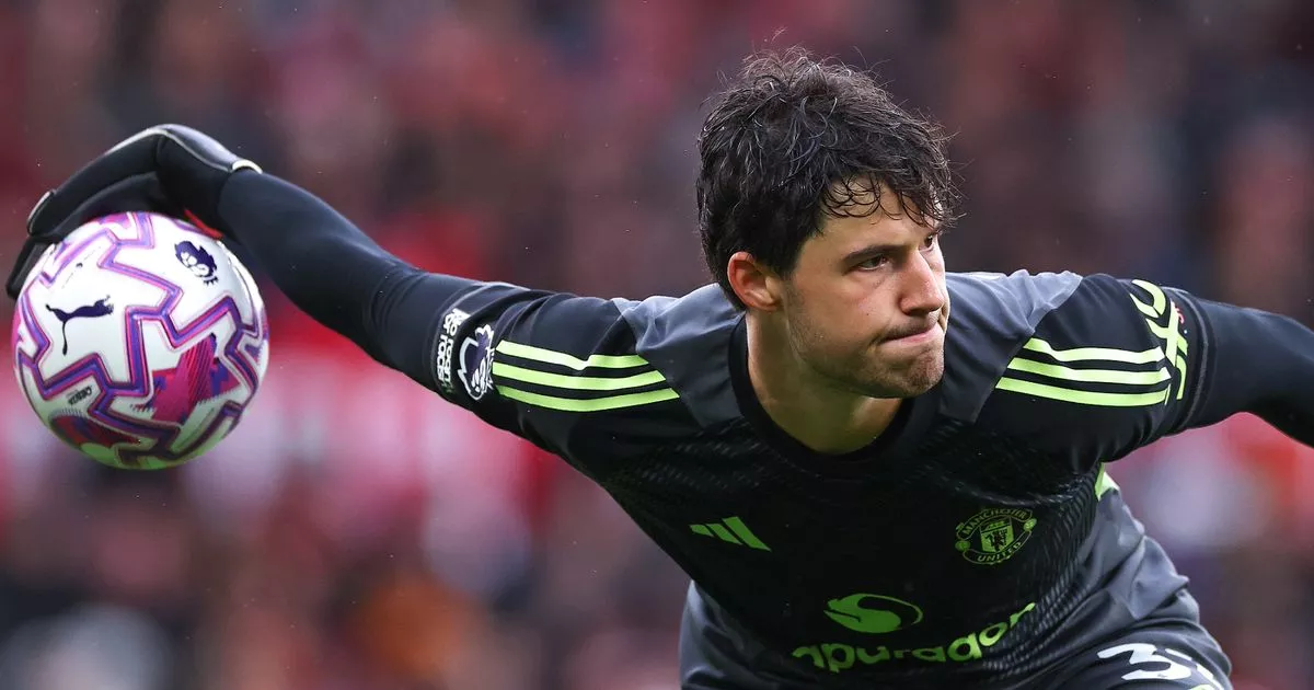 Senne Lammens making a save in a Manchester United jersey.