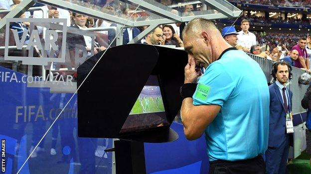 VAR officials reviewing a decision during an international football match.